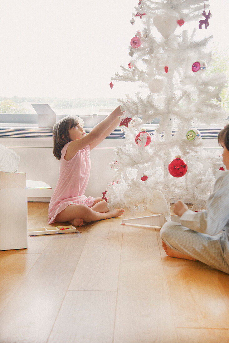 Junges Mädchen schmückt Weihnachtsbaum