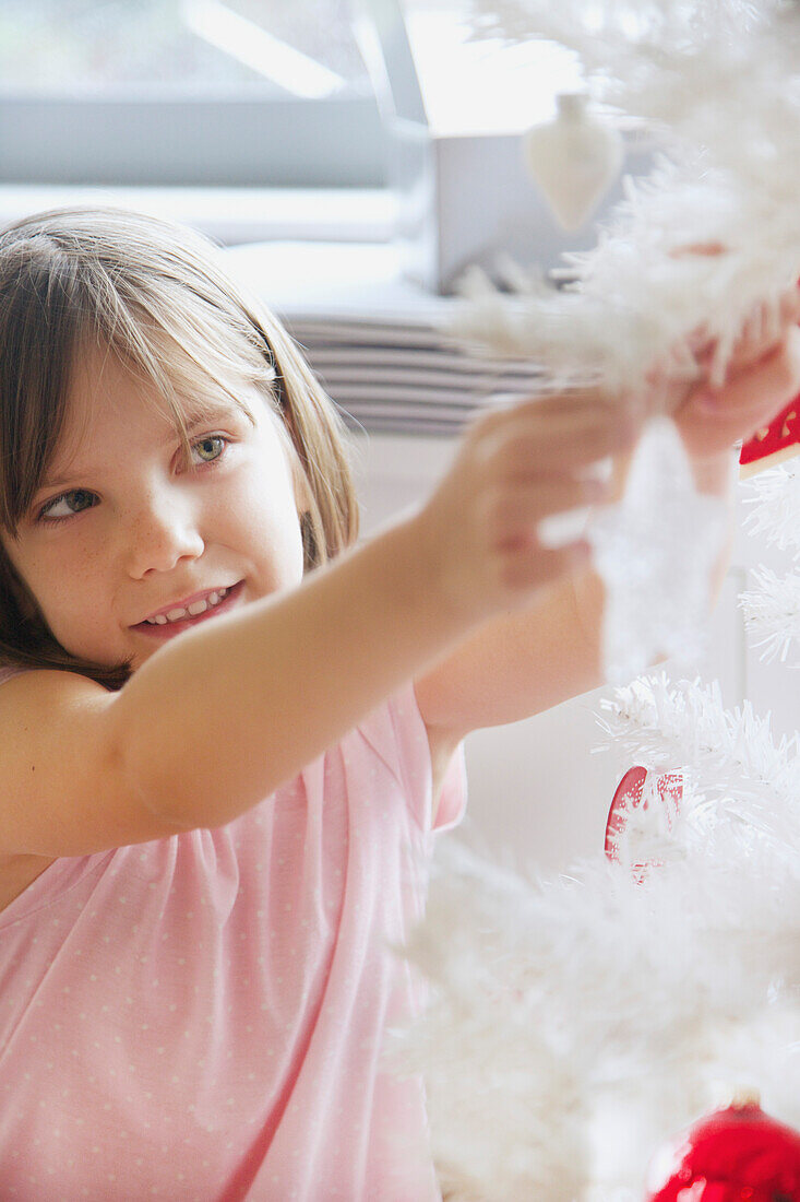 Nahaufnahme eines jungen Mädchens beim Schmücken des Weihnachtsbaums