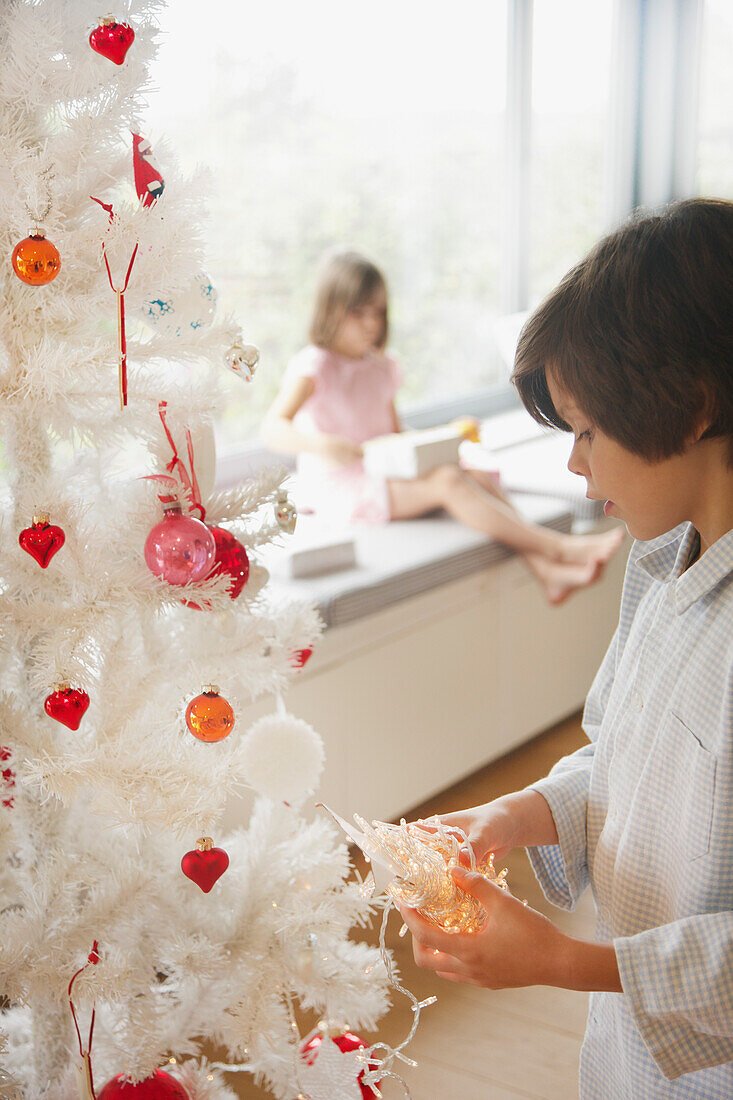 Junger Junge beim Schmücken des Weihnachtsbaums