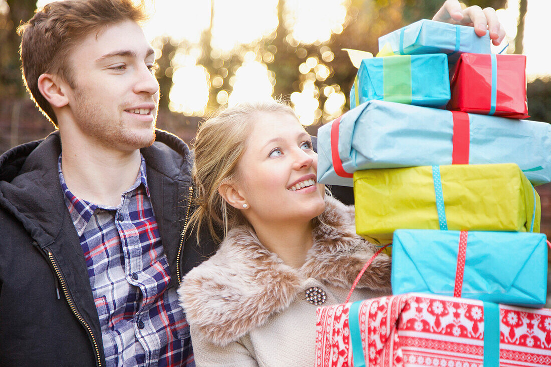 Junges Paar hält Stapel von Weihnachtsgeschenken im Freien