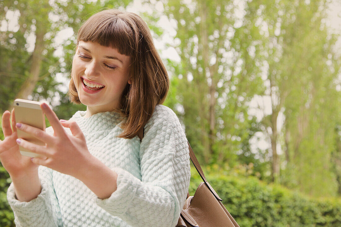 Lächelndes Mädchen im Teenageralter mit Smartphone im Freien