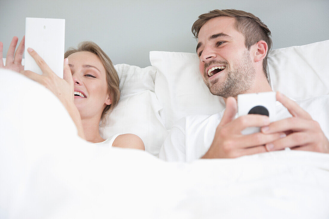 Ehepaar im Bett mit Smartphone