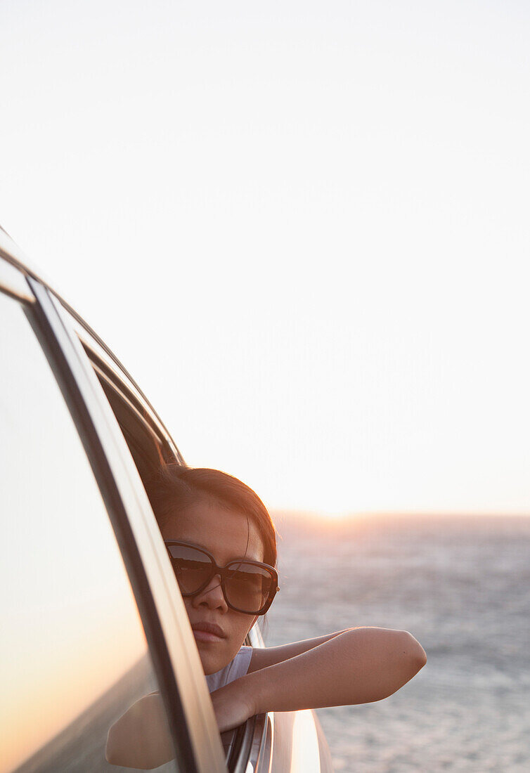 Frau schaut bei Sonnenuntergang aus dem Autofenster