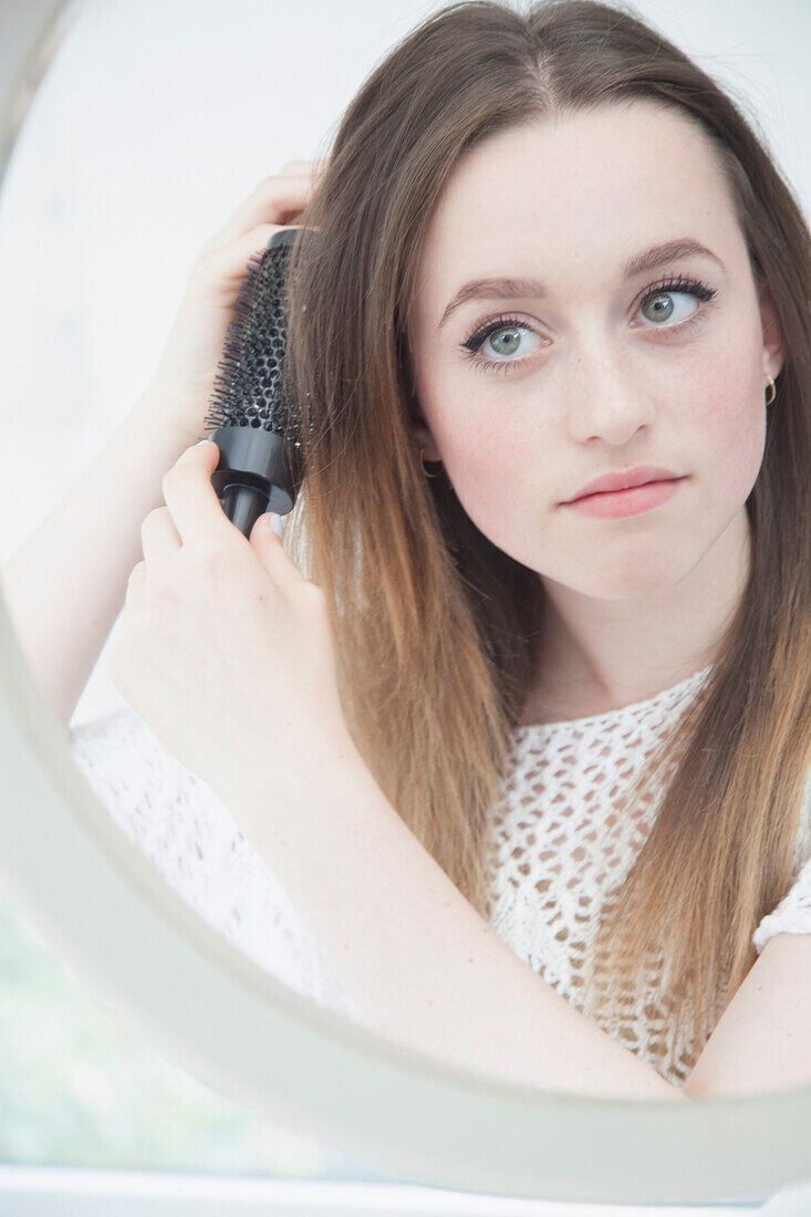 Teenage Girl Looking in Mirror Brushing her Hair