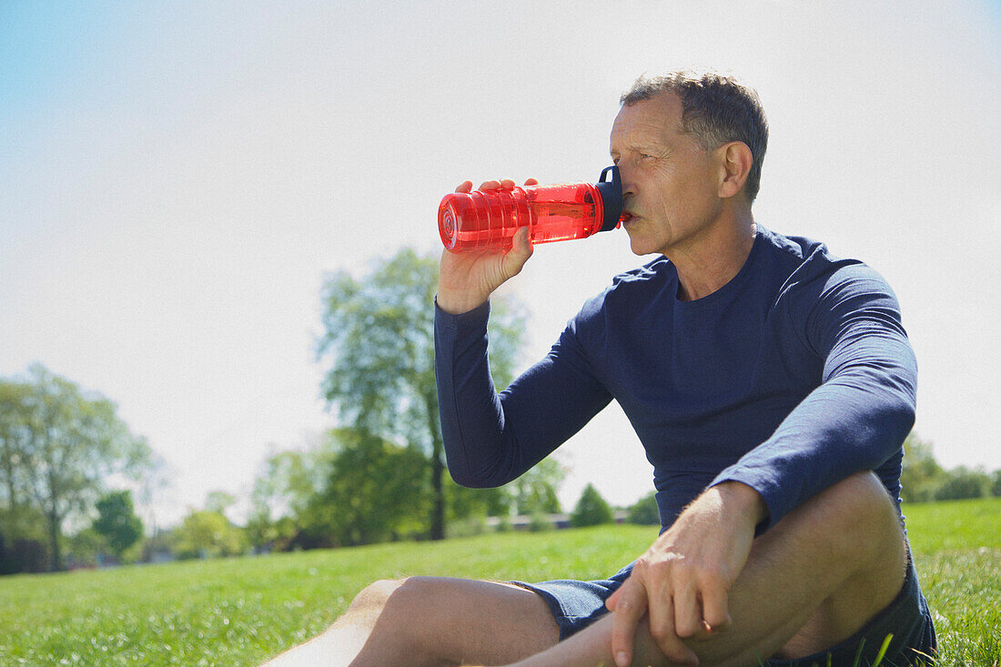 Älterer Mann trinkt aus einer Wasserflasche im Park