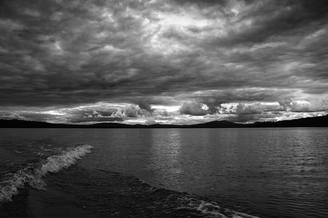 Boat wake on lake with dramatic clouds