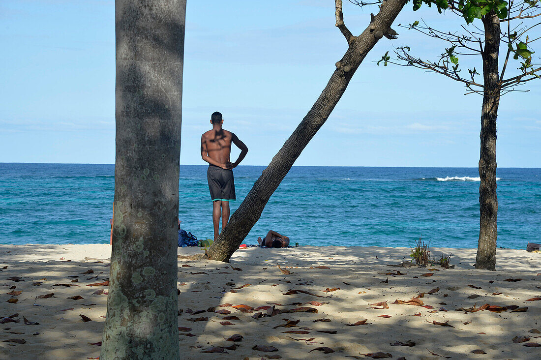 Cuba ,Baracoa,Maguana beach,,homme,a man shirtless is standing on a tree trunk facing the sea