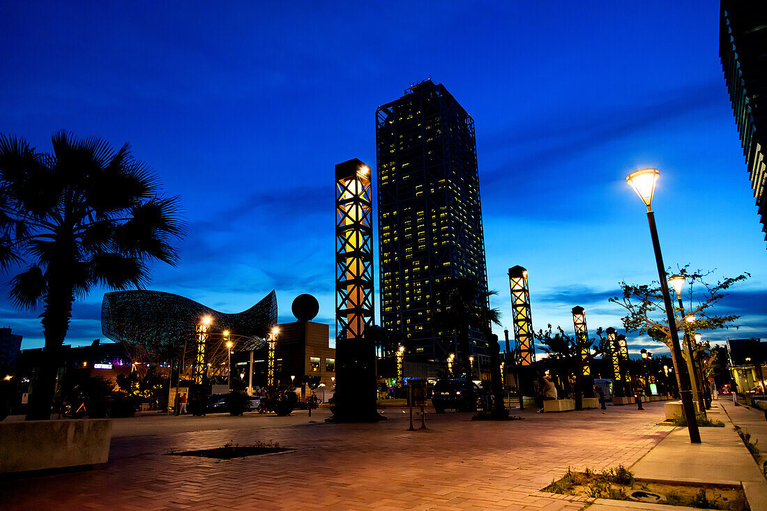 BARCELONA,SPANIEN - 2. JUNI 2019: Gehry Fischskulptur und Torre Mapfre (arch. Ortiz Leon Arquitectos) bei Nacht. Mittelmeerküste, Vila Olímpica del Poblenou in Barcelona, Spanien.