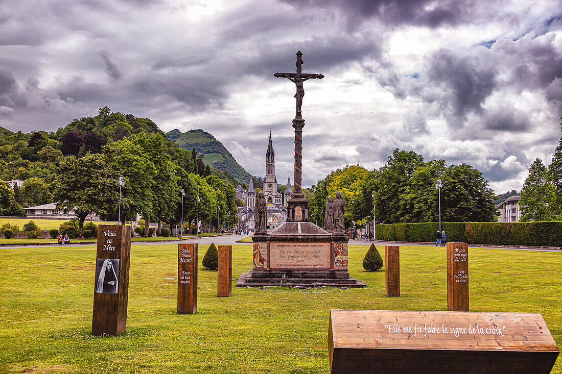 LOURDES - 15. JUNI 2019: Christliches Kreuz auf dem Hintergrund der Basilika Unserer Lieben Frau vom Rosenkranz in Lourdes,Frankreich