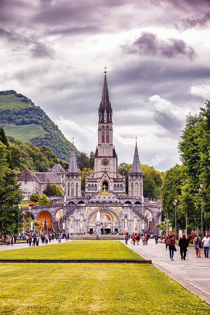 LOURDES - 15. JUNI 2019: Christliches Kreuz auf dem Hintergrund der Basilika Unserer Lieben Frau vom Rosenkranz in Lourdes,Frankreich