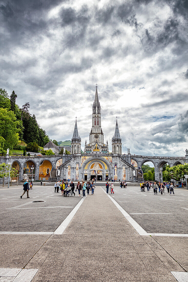 LOURDES - 15. JUNI 2019: Christliches Kreuz auf dem Hintergrund der Basilika Unserer Lieben Frau vom Rosenkranz in Lourdes,Frankreich