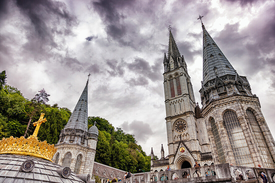 LOURDES - 15. JUNI 2019: Christliches Kreuz auf dem Hintergrund der Basilika Unserer Lieben Frau vom Rosenkranz in Lourdes,Frankreich