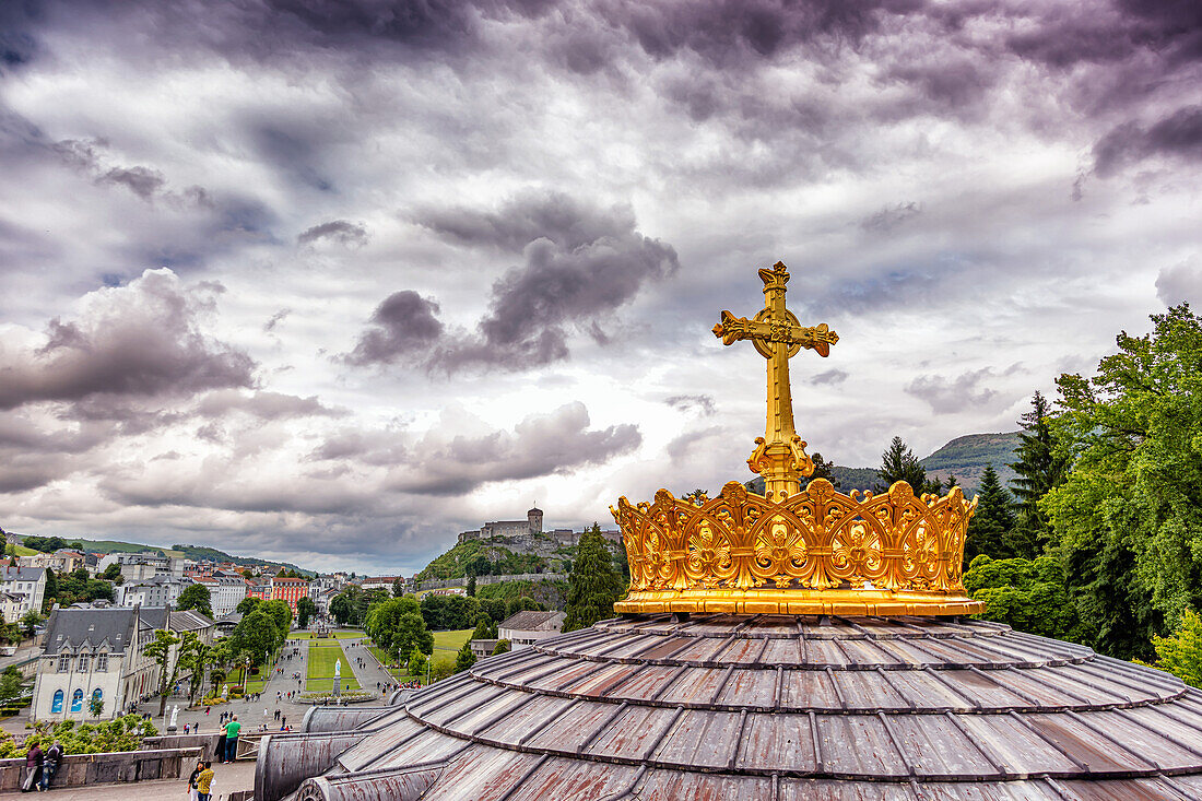 LOURDES - 15. JUNI 2019: Christliches Kreuz auf dem Hintergrund der Basilika Unserer Lieben Frau vom Rosenkranz in Lourdes,Frankreich