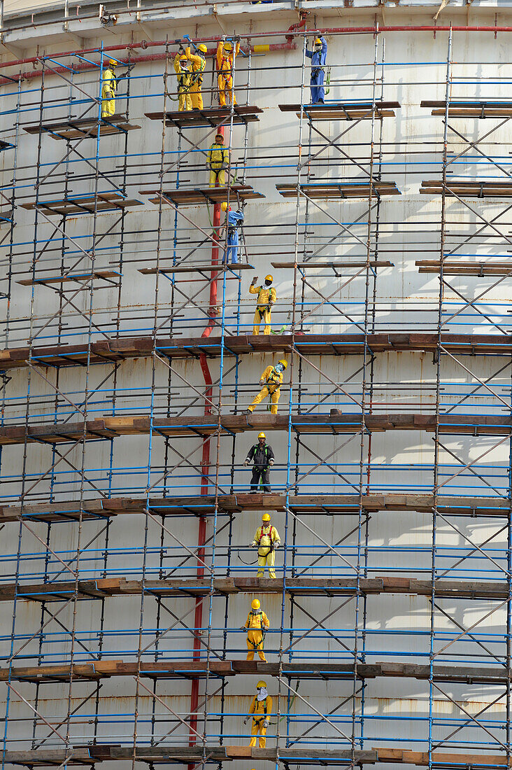 Sultanate of Oman,Oman,DHOFAR, Indian workers in yellow overalls stand on huge scaffolding at Salalah port