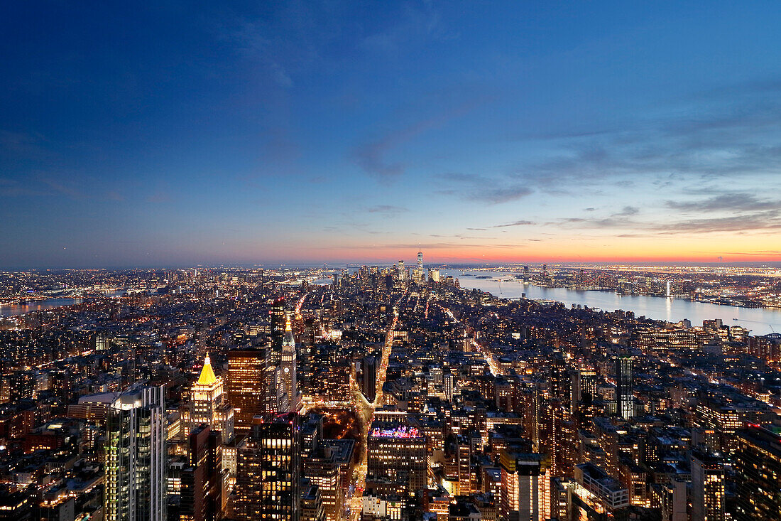 USA. New York City. Manhattan. Empire State Building. Blick von der Spitze des Gebäudes in der Abenddämmerung und bei Nacht. Blick auf das One World Trade Center und die Unterstadt. Der Hudson River ist rechts zu sehen.