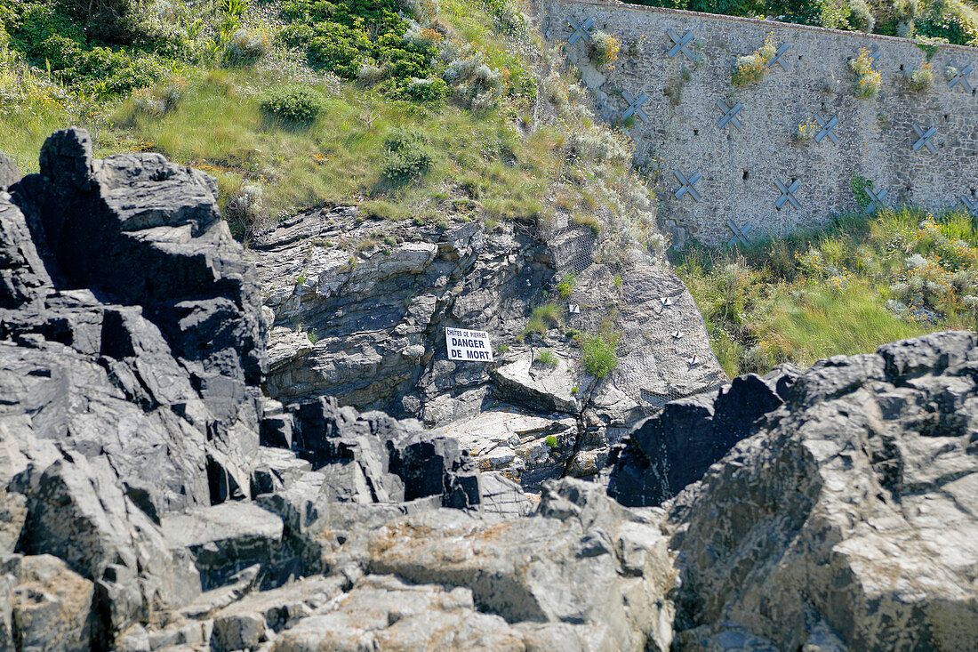 France. Normandy. Department of Manche. Granville during the summer. View from the coast and part of the beach. Dangerous rocks due to falling rocks and rocks. Danger of death sign.