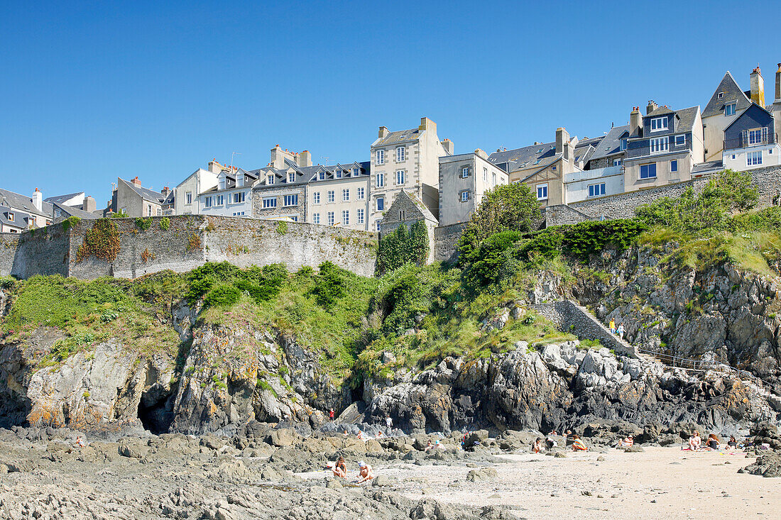 France. Normandy. Department of Manche. Granville during the summer. View from the coast at ebb tide. Tourists sunbathing.