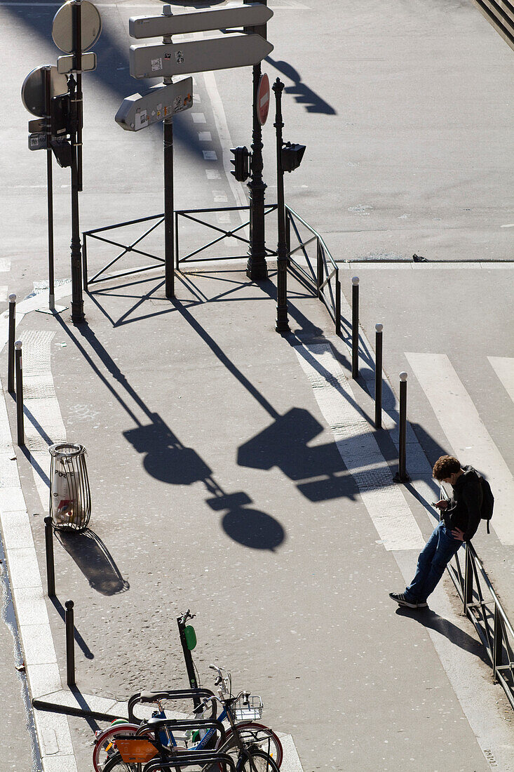 France,Paris,75,8th arrondissement,Rue Tronchet,young man looking at his phone on an empty esplanade,winter;