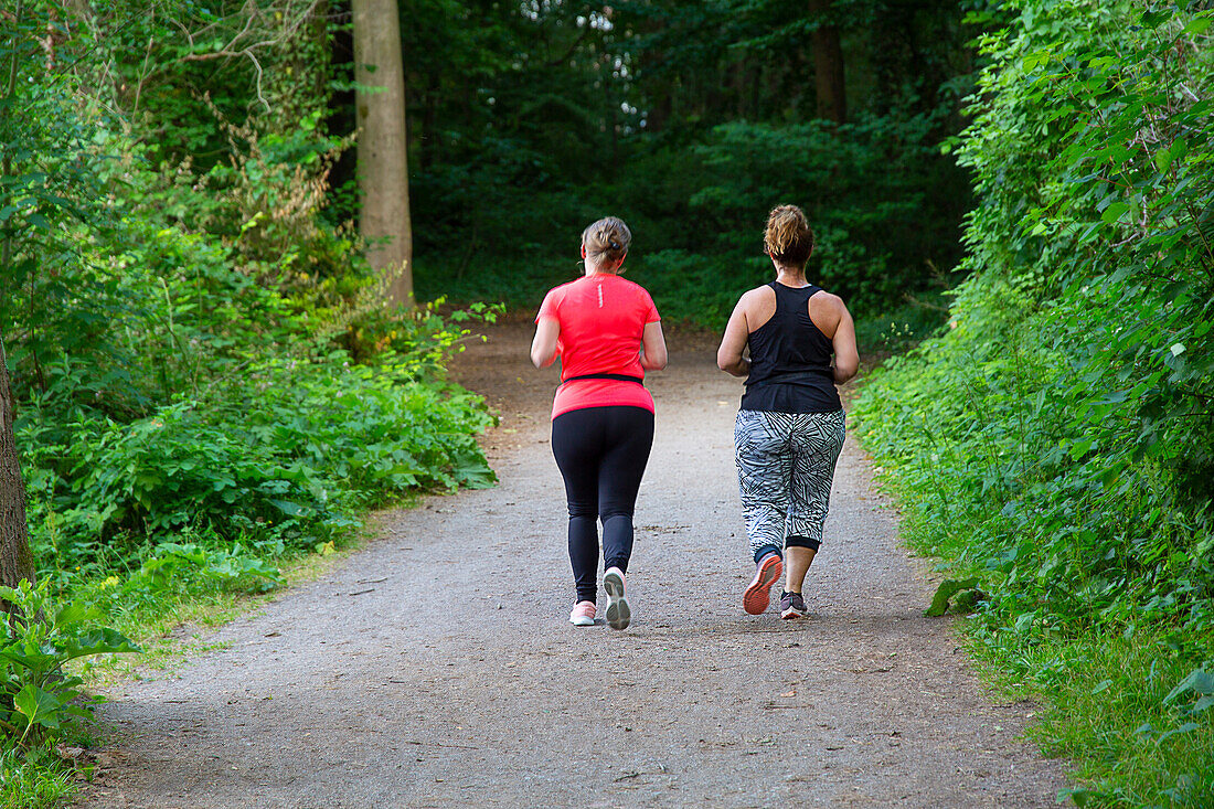 Two women from the back in the forest jogging