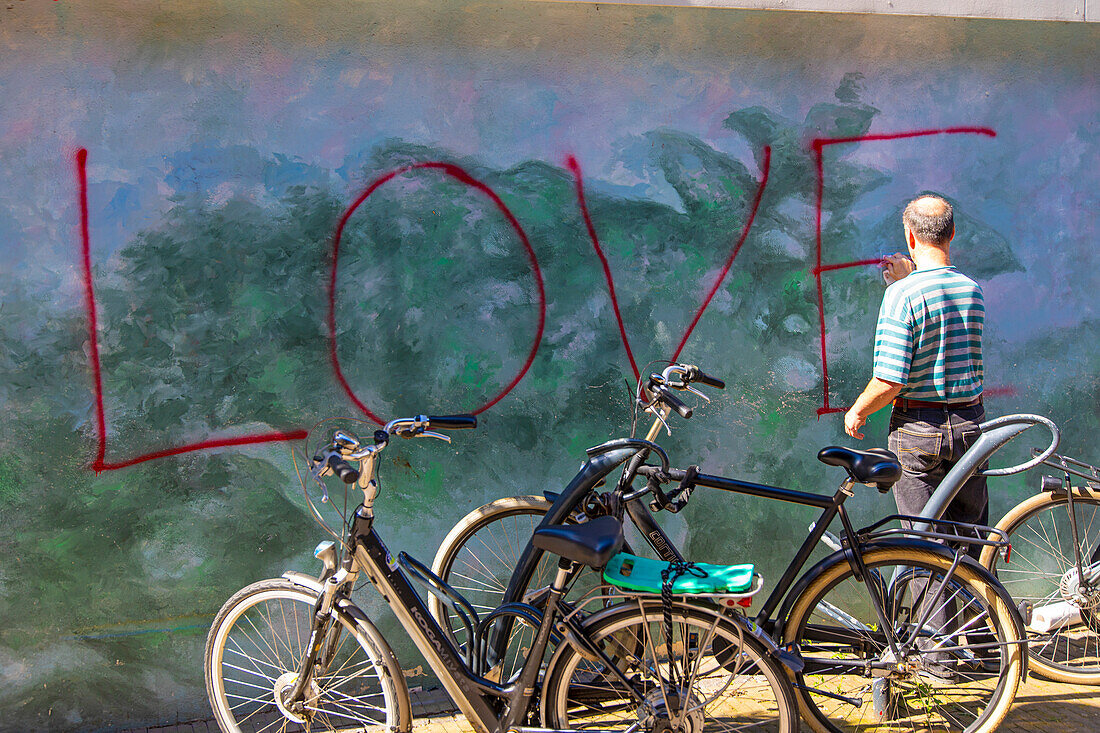 Wall with graffiti. A man erases the paint