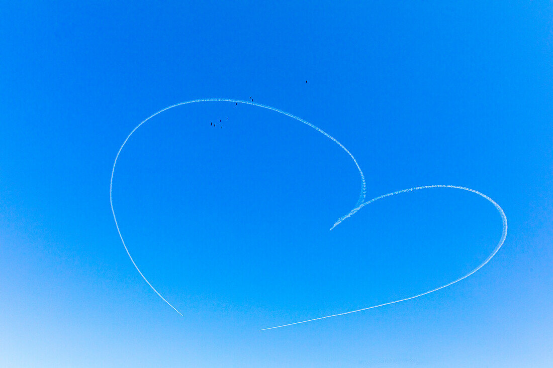 Two planes draw a heart in a blue sky