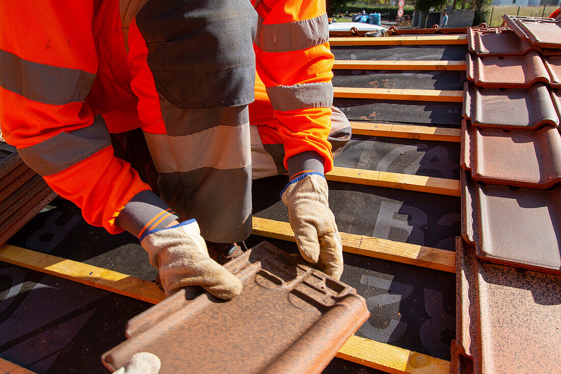 Worker installing tiles on a roof