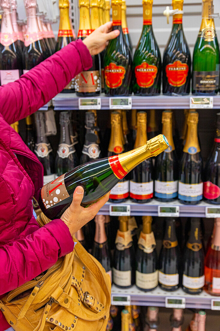 Blonde Frau beim Einkaufen im Supermarkt während einer Weinmesse. Champagner Moët et Chandon