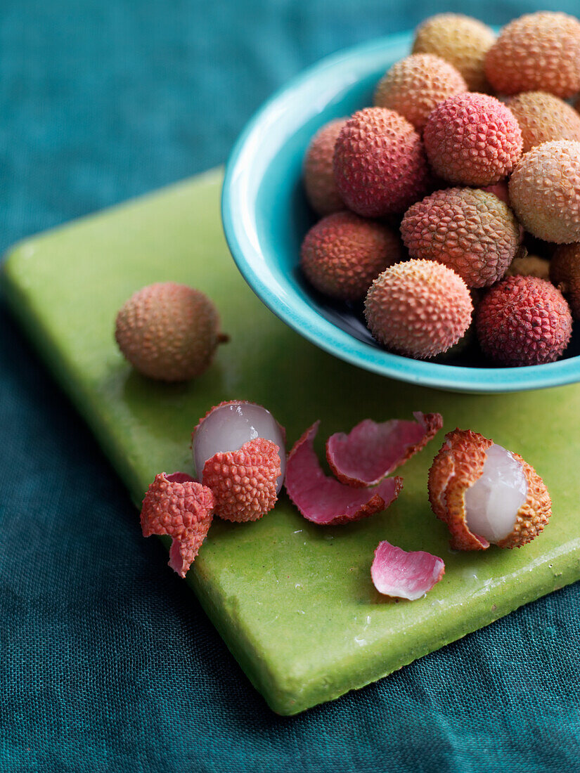 Whole and peeled lychees in a bowl