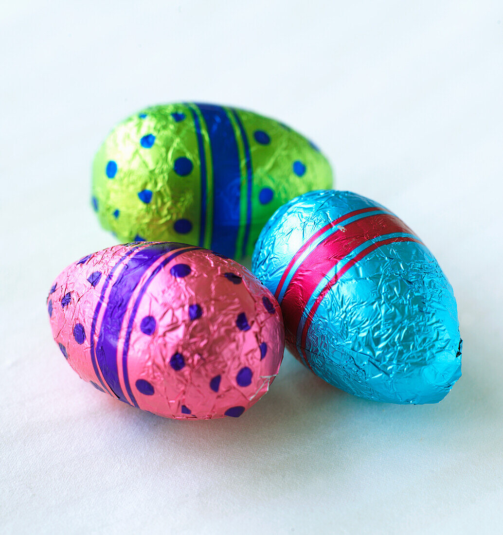 Three colourfully wrapped chocolate eggs