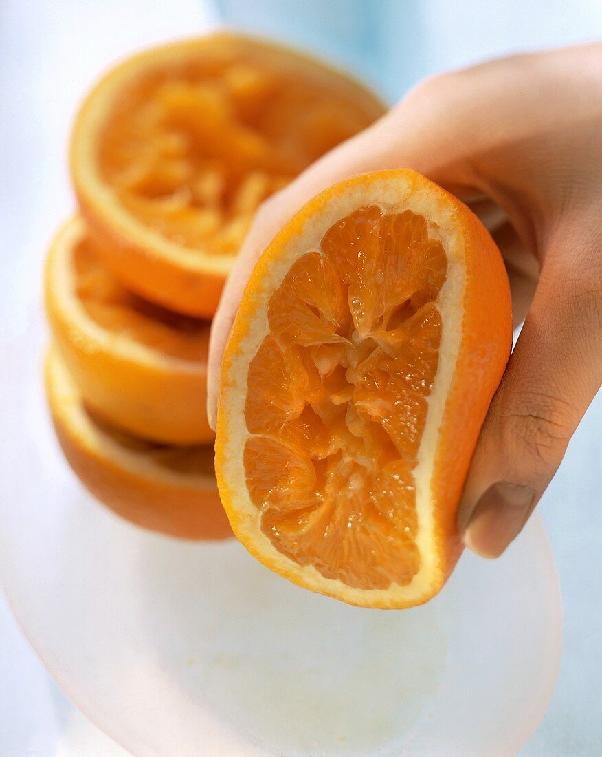 Orangenhälfte wird von Hand ausgepresst