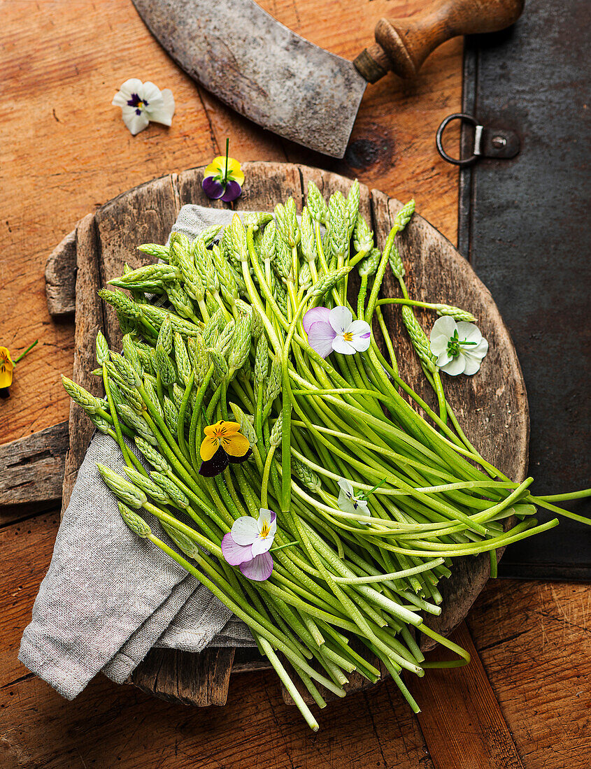 Wild asparagus on a wooden board with edible flowers