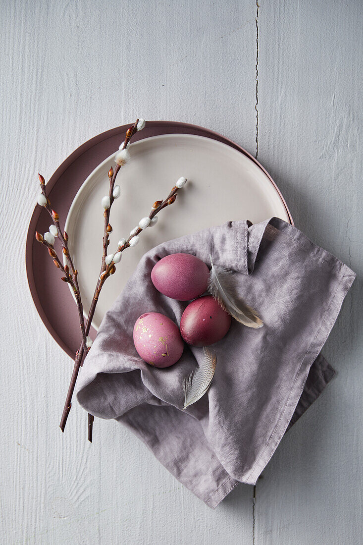 Pink Easter eggs with pussy willows on a purple napkin and pink plate