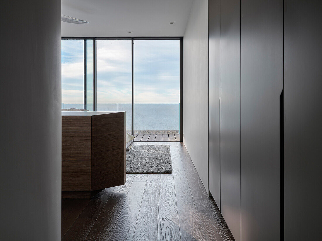 Wooden floor and large glass front in room with sea view