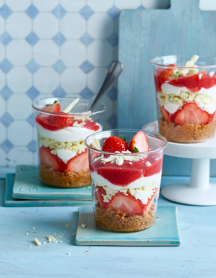 Layered strawberry dessert in a glass with cream and cookie base