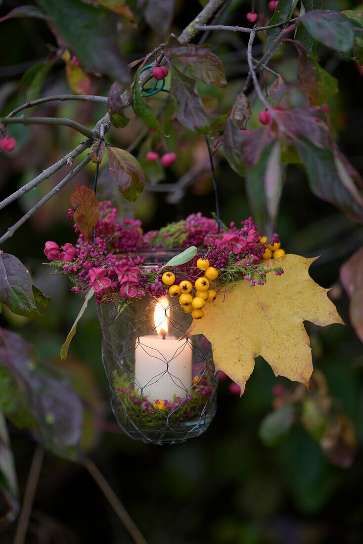 Windlicht mit Heidekraut-, Pfaffenhütchen- und Feuerdornkranz im Garten