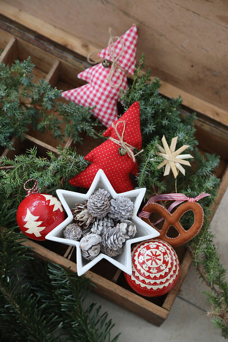 Wooden box with red and white Christmas decorations, star bowls, cones and baubles