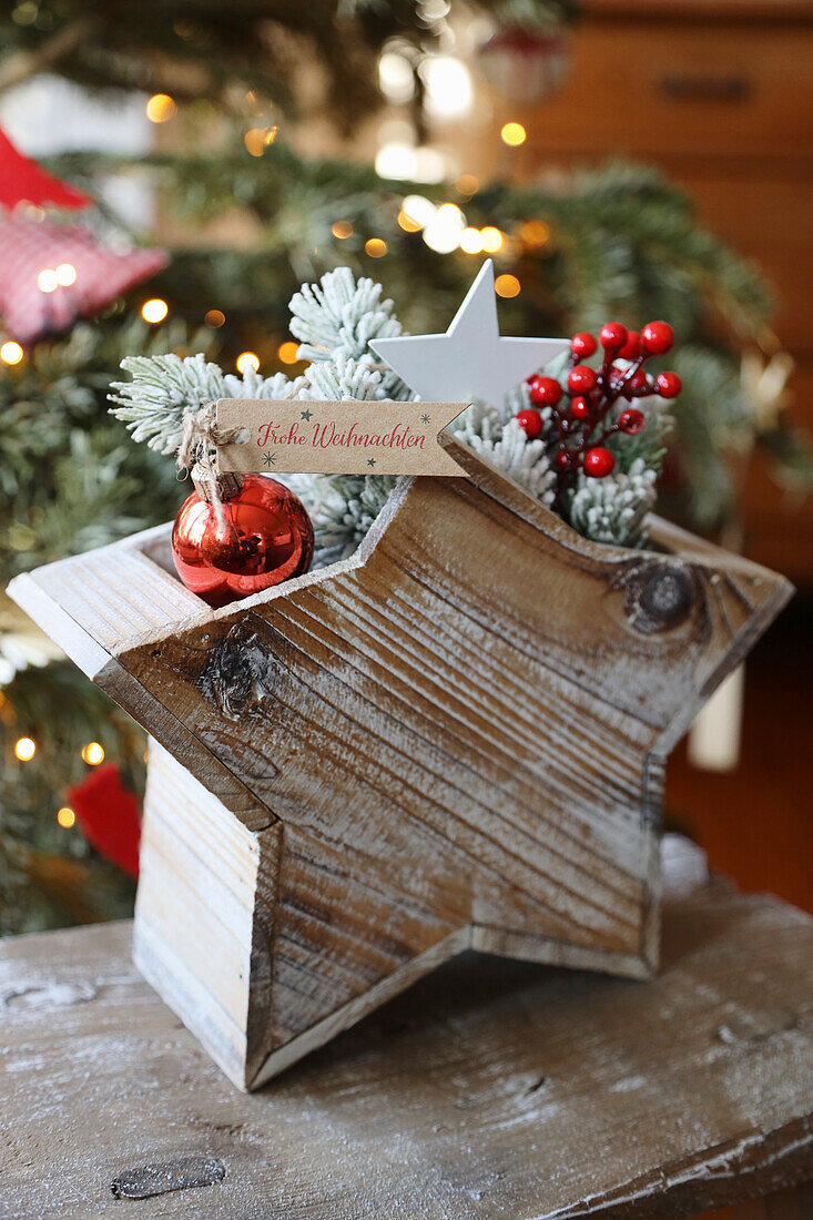 Wooden star with Christmas decorations, glass ball, twig, berries, Christmas greetings