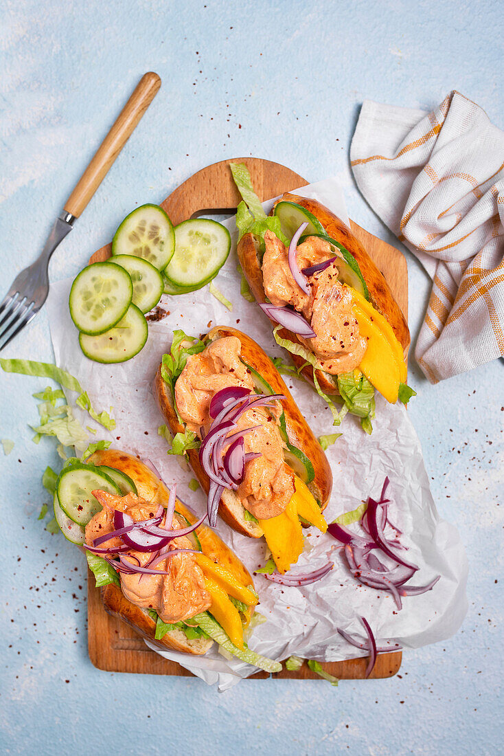 Hotdogs mit Garnelen, Gurke, Mango und Zwiebeln