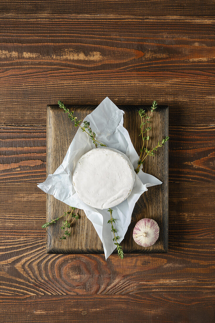 Camembert on a wooden board with thyme and garlic