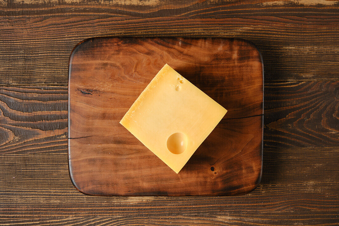 A slice of Emmental on a wooden board