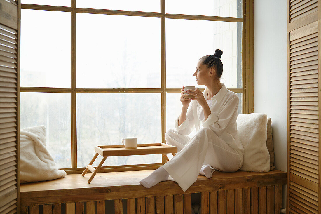 Woman sitting at the window with a teacup