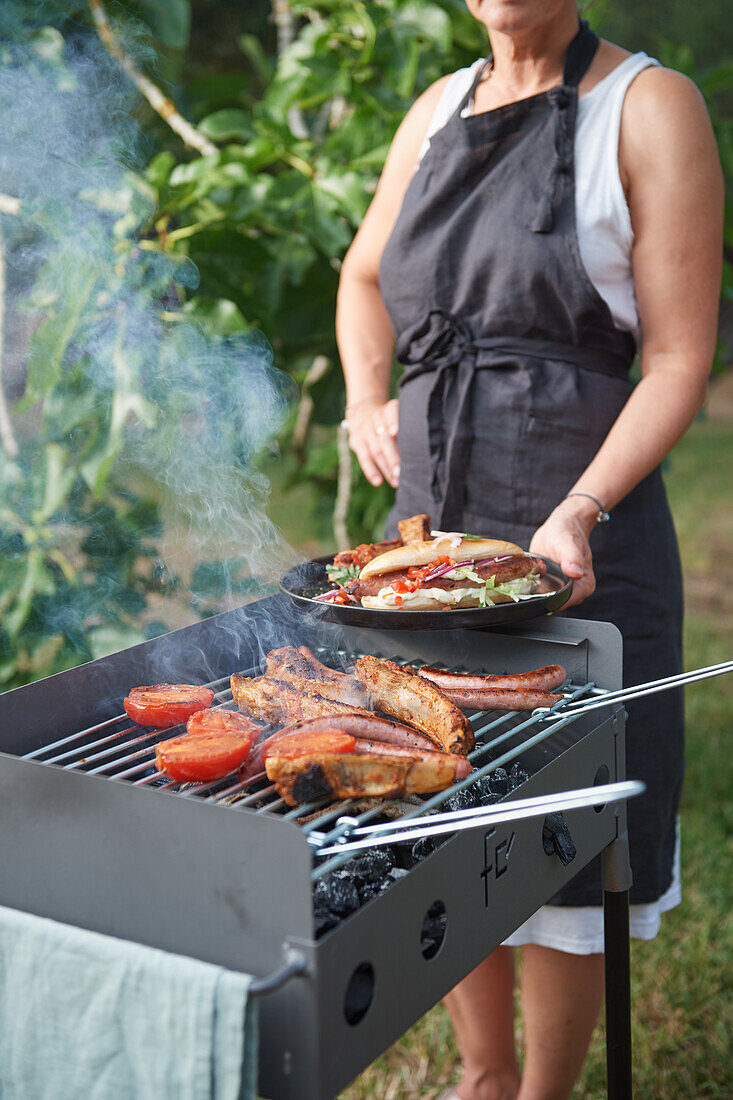 Frau grillt Hot Dogs und Spareribs