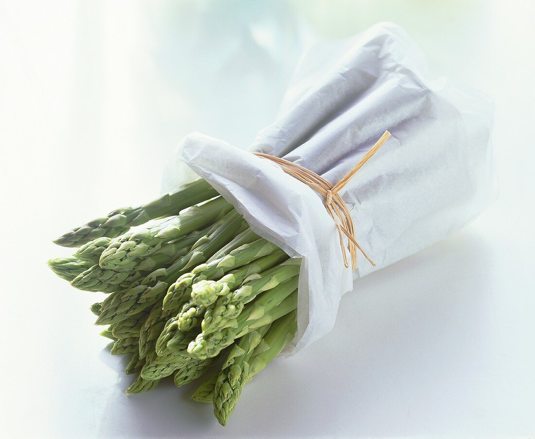A bundle of green asparagus wrapped in white paper