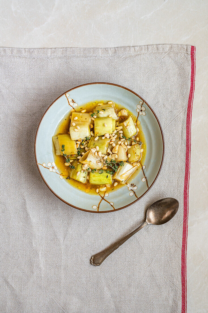 Leek in broth with garlic, thyme and pine nuts