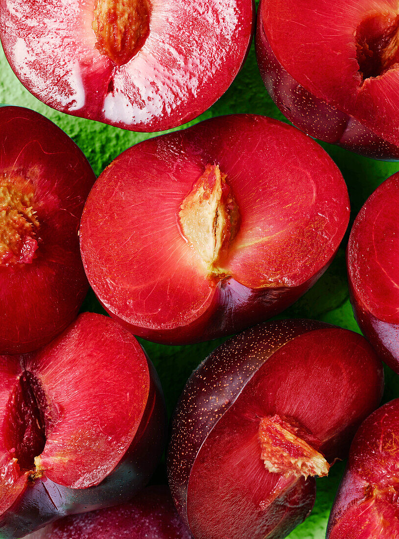 Halved plums on a green background