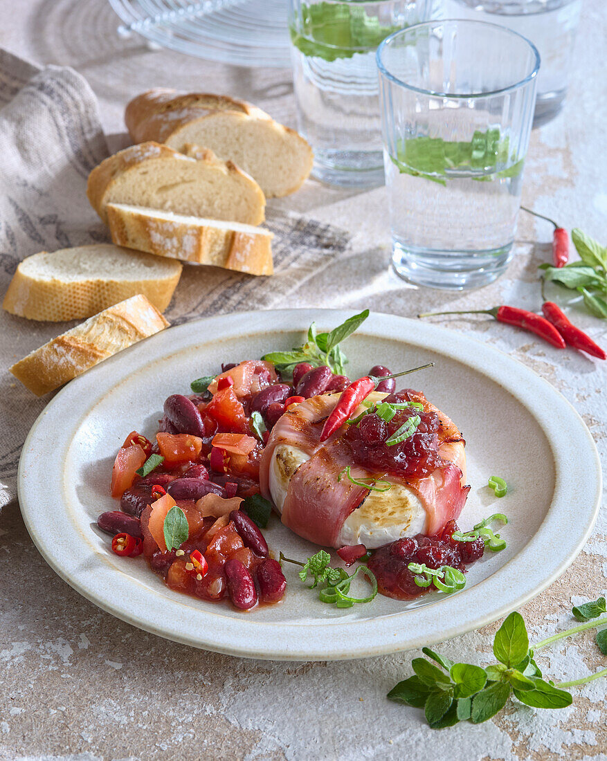 Grilled camembert wrapped in bacon with spicy beans