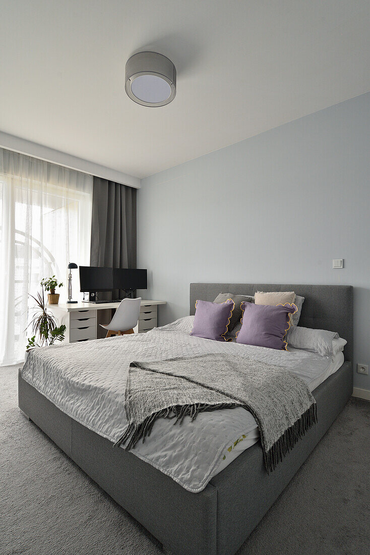 Bedroom with grey bed, work area and indoor plants