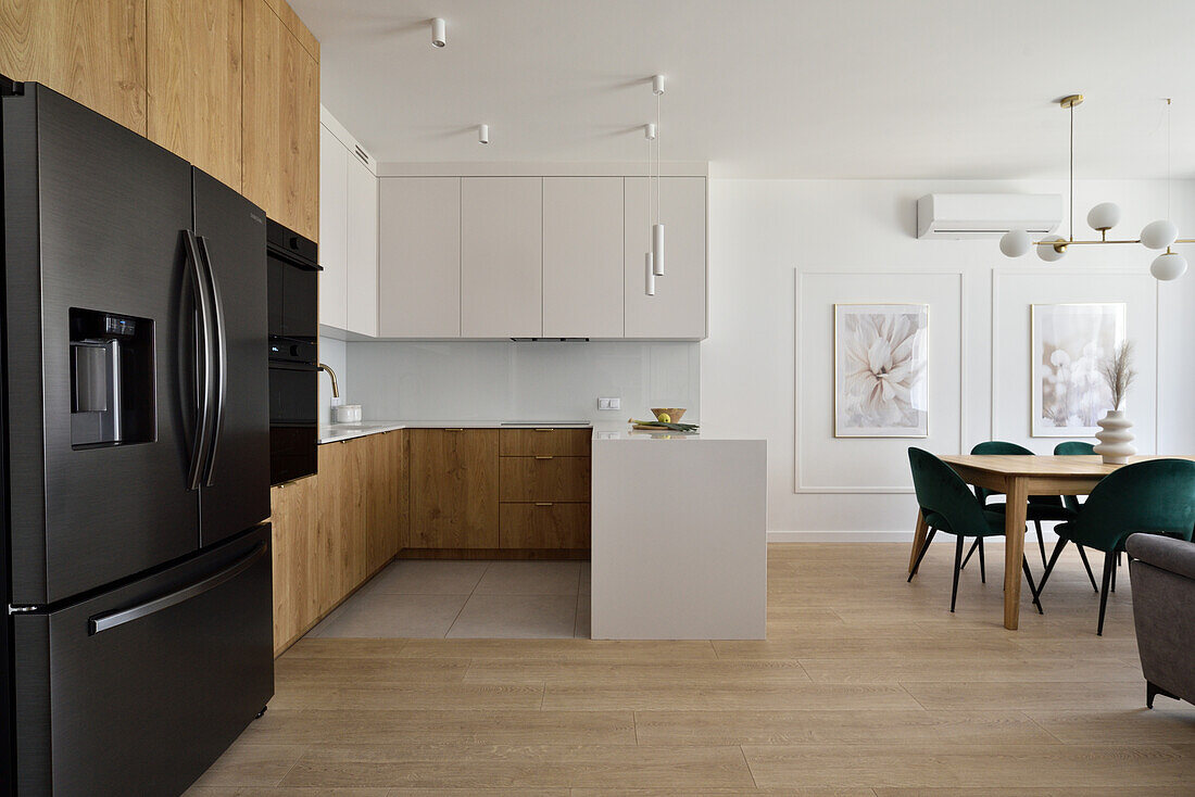 Modern kitchen and dining area with black kitchen appliances and wooden and white cupboards