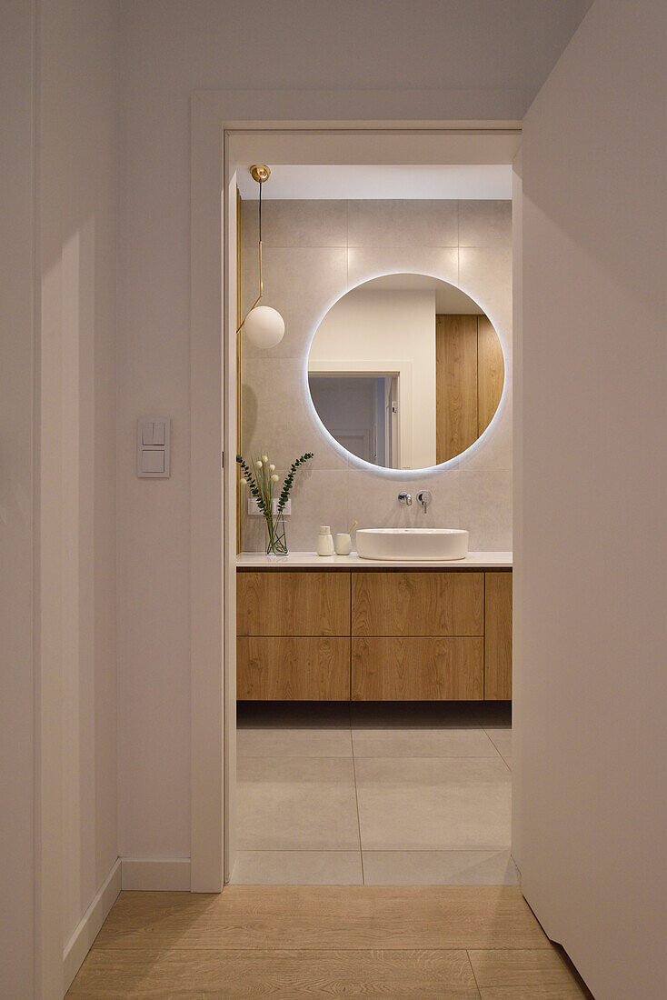 Modern bathroom with wooden washbasin and round mirror