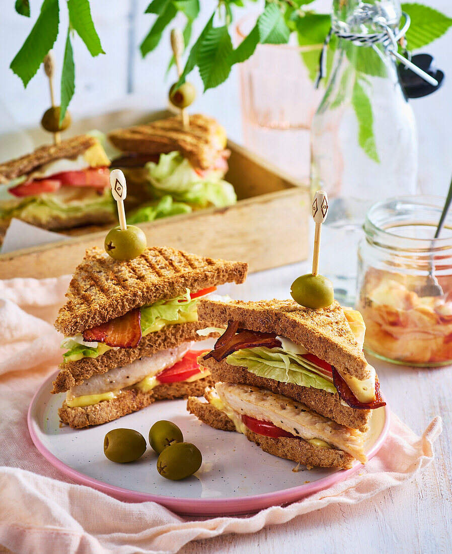 Turkey club sandwich with bacon, salad and olives